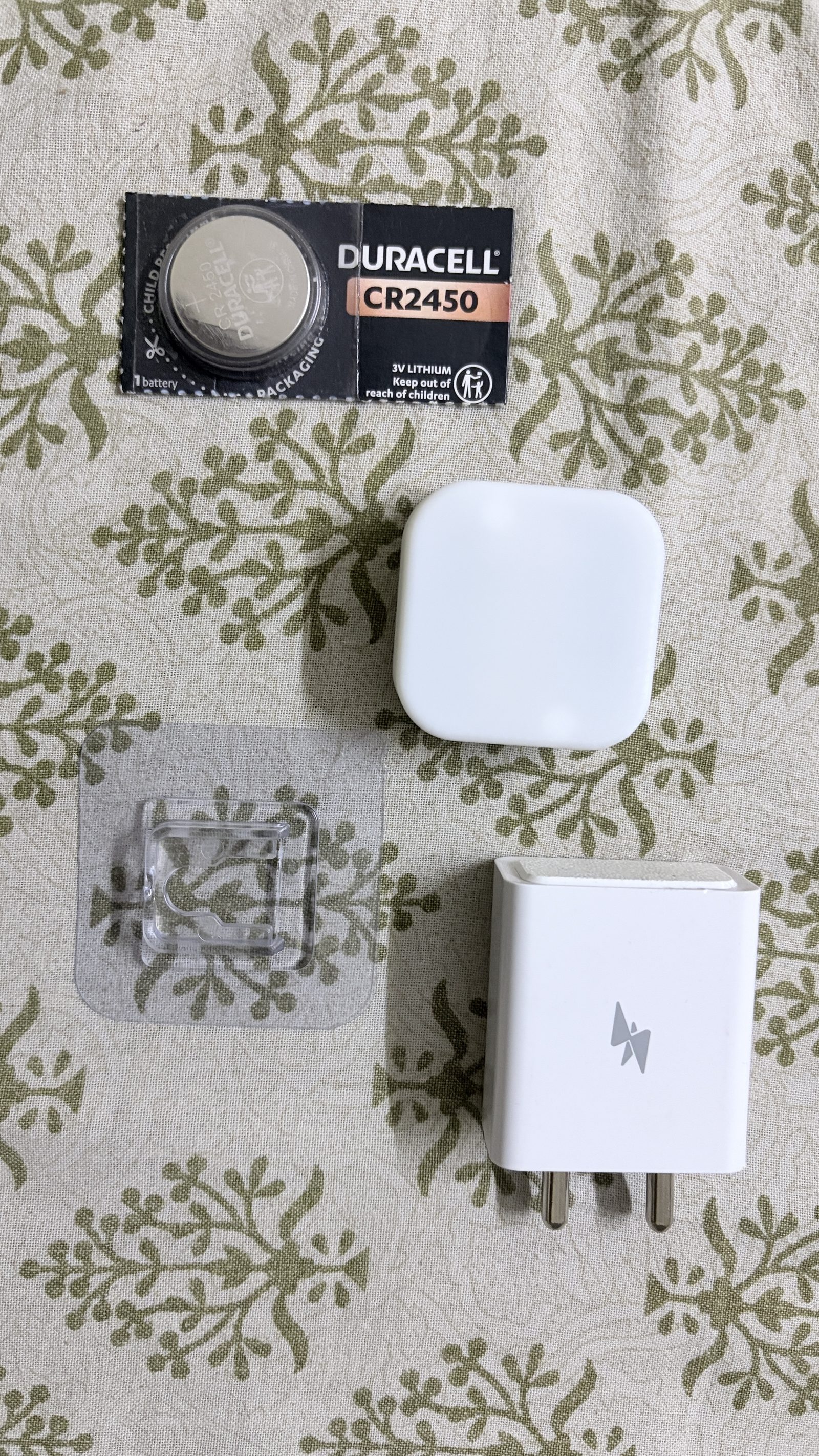 Aura kit contents: CR2450 battery, Aura Dot housing, adhesive female hook, and Aura Core charger.