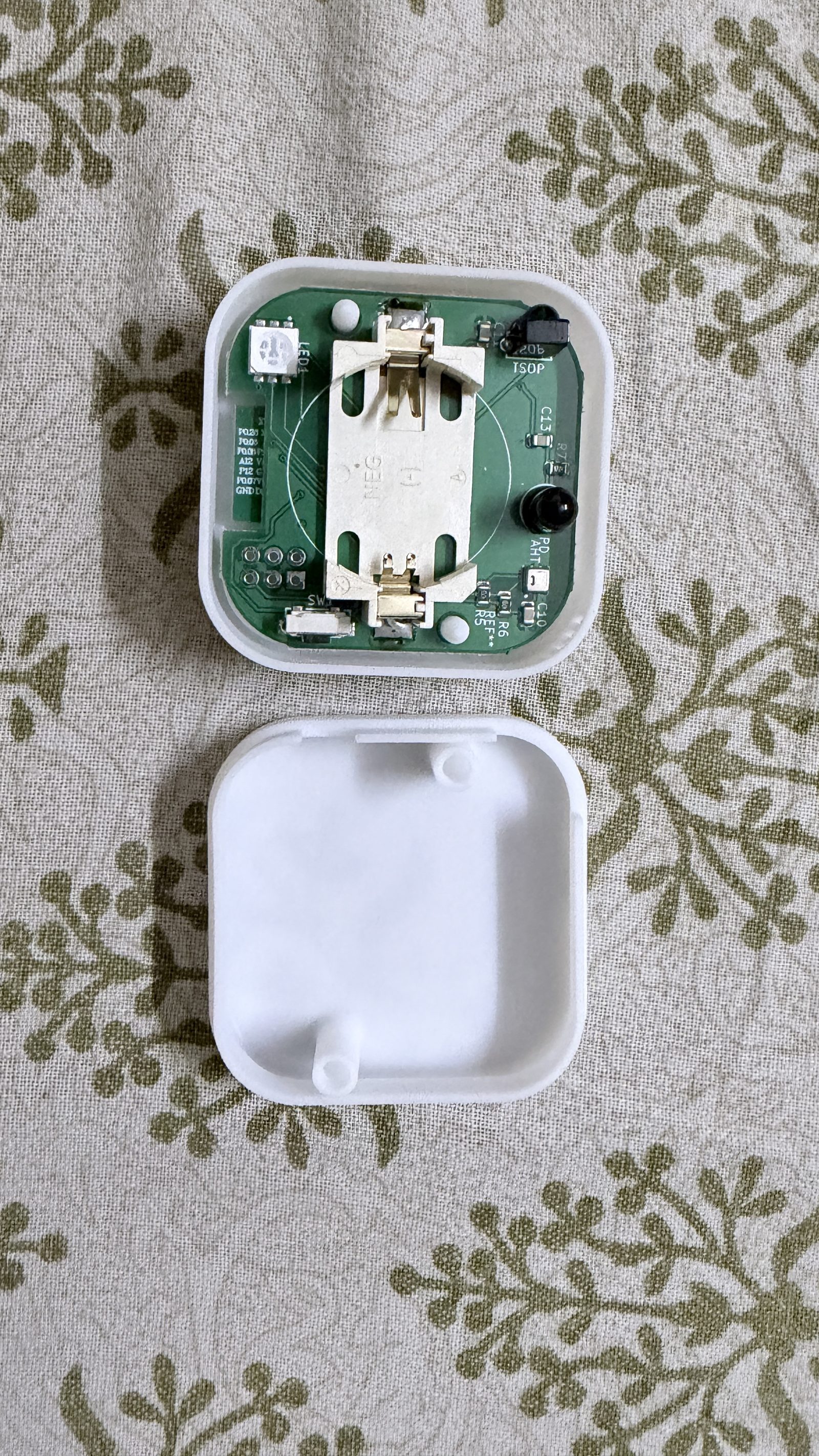 The Aura Dot opened up, showing the empty CR2450 holder on the PCB.